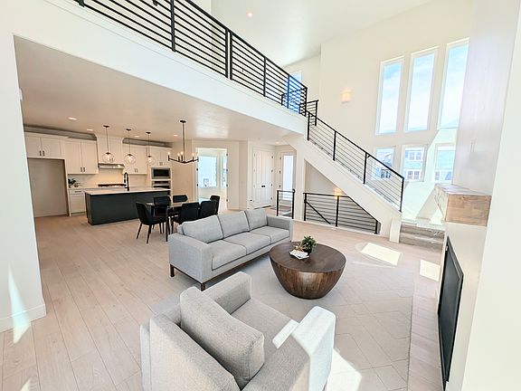 Modern, open-concept living space designed for the innovator, with light wood floors, a gray sofa, a