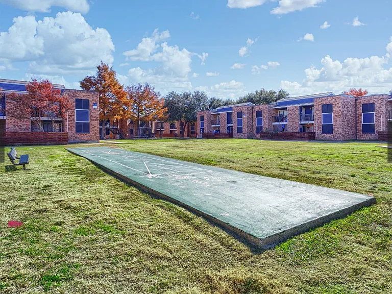 Unwind and have fun at the outdoor game court area _ a great spot for residents to enjoy bocce ball, cornhole, or simply gather with neighbors in the open green lawn.