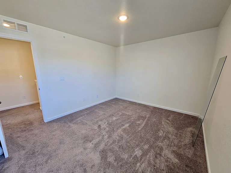 Second bedroom viewed from the window corner to show spacious layout for easy arrangement.