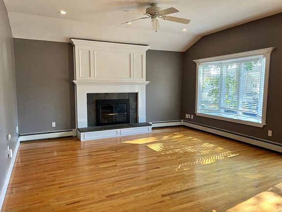 Living room, mantle, bay window & tray ceiling with ceiling fan and recessed lighting.