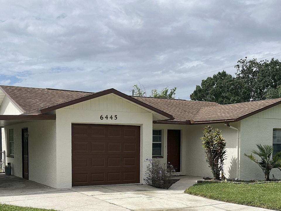 Front of house: one-car carport, one-car garage, front-door entrance and side-door entrance into garage.