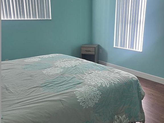 Private bedroom with two windows, wood-look flooring, and space for a full/queen bed plus a nightstand.