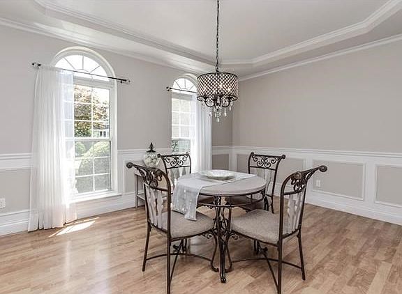 Elegant formal dining room featuring tray ceilings and gracious arched windows.