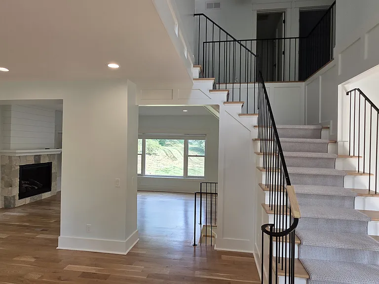 View at front door lookin into living area and stair case to upper floor. Carper runner up center of staircase.