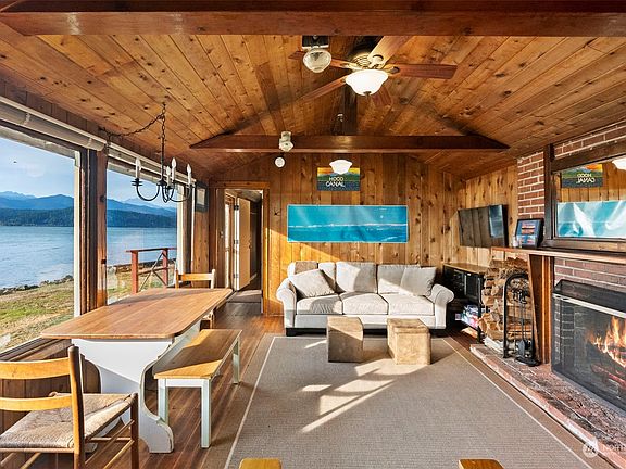 Living room and dining area with original wood floors, vaulted ceiling and fireplace to keep you warm on those chilly nights. Large windows to take in the gorgeous views of Hood Canal and Olympic Mountains.>