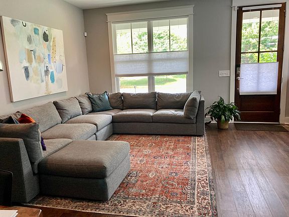 Living room with shades that let in light and are private. Front door. Actual.