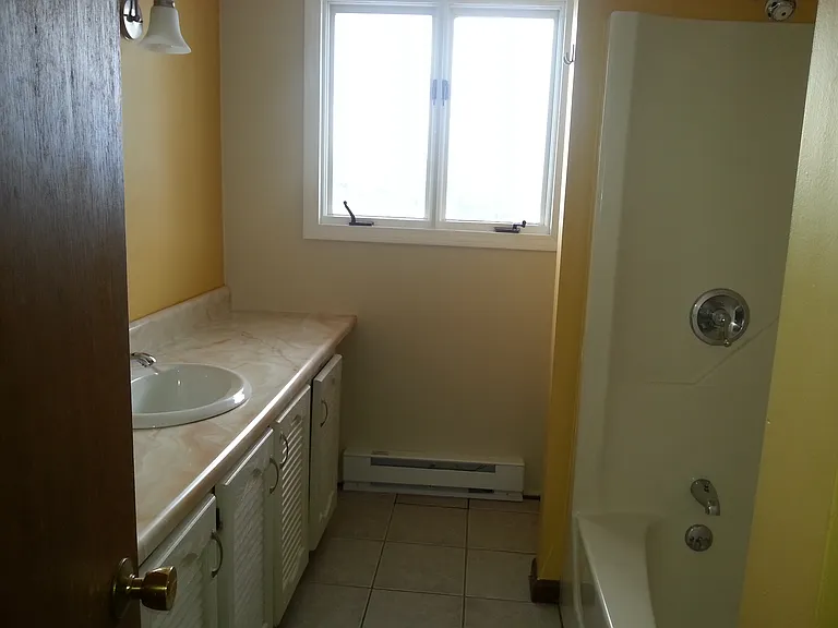 Full bath, tile floor, tub with shower, large vanity and tons of cabinets behind door and under sink