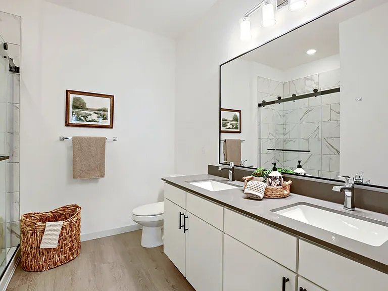 The primary en suite features a double vanity and a walk-in glass shower with designer tile _ your own spa retreat. Garrett Harvest Junction West, Longmont, CO.