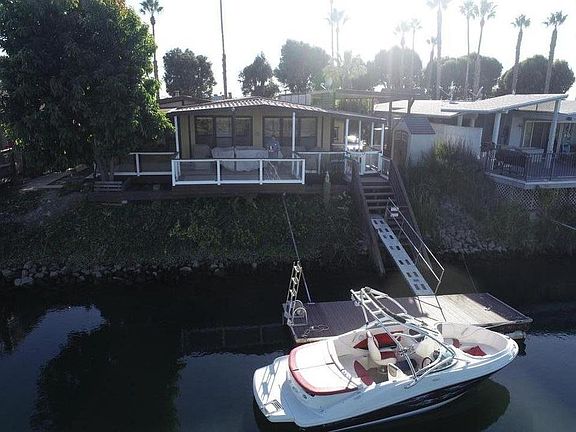View of deck patio from the river. The river is about 70 yards wide and 40 plus feet deep. Along the left side of home is a fruit tree orchid. Along rt side is a over size carport bay. Easil fits two full size SUV's with EV/RV outlet. The outdoor kitc