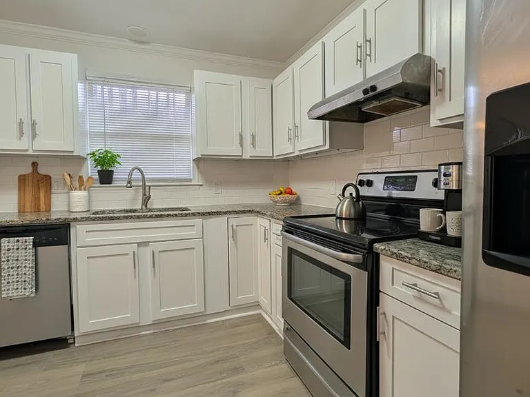 U-shaped kitchen with shaker cabinetry, granite-look counters, subway tile backsplash, and stainless steel appliances.