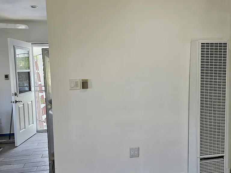 Front room, with wall heater. The left side looks towards dining room and rear door.