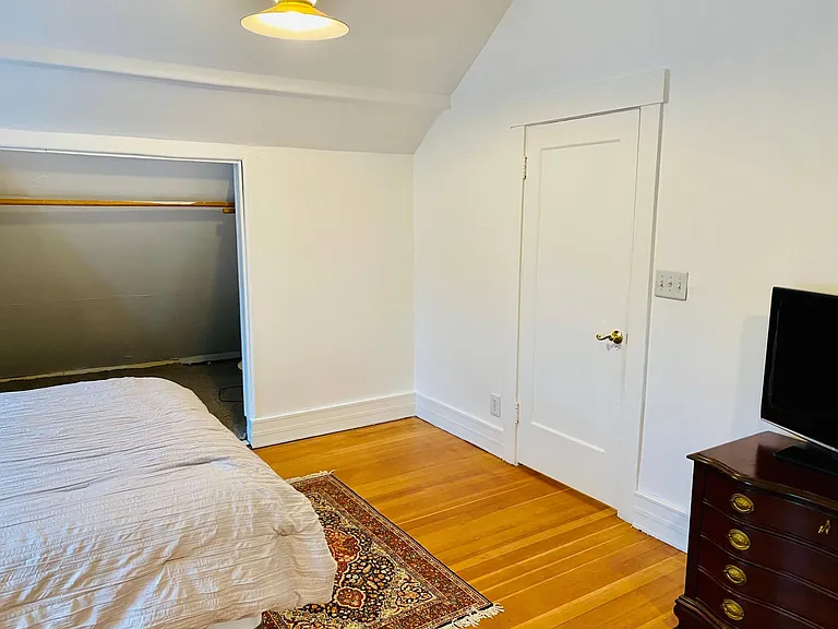 bedroom with door access to bathroom and kitchen/ living room beyond