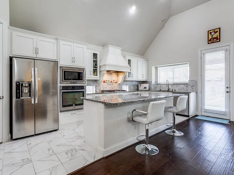 Kitchen featuring premium range hood, backsplash, stainless steel appliances, light hardwood / wood-style floors, and white cabinets
