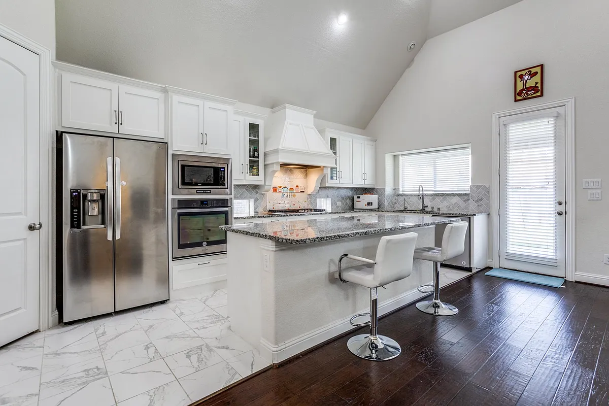 Kitchen featuring premium range hood, backsplash, stainless steel appliances, light hardwood / wood-style floors, and white cabinets - 821 Yarrow St
