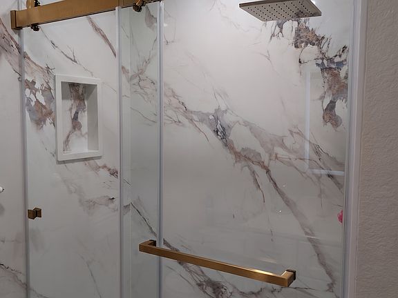 Primary bathroom fully remodeled with stone finished walk-in shower, glass doors, Delta hardware, and brand new shower pan.