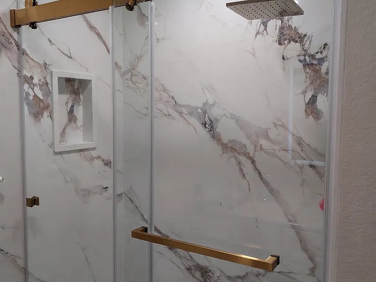 Primary bathroom fully remodeled with stone finished walk-in shower, glass doors, Delta hardware, and brand new shower pan.