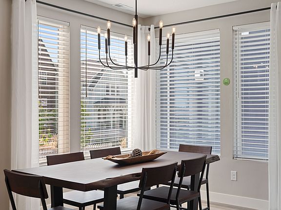 The dining area at Cascade Village features a wooden table, four chairs, and a modern chandelier, al