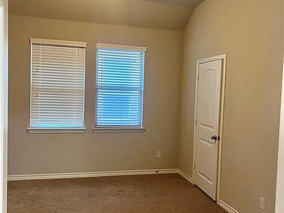 Unfurnished room featuring dark carpet, lofted ceiling, and a textured ceiling