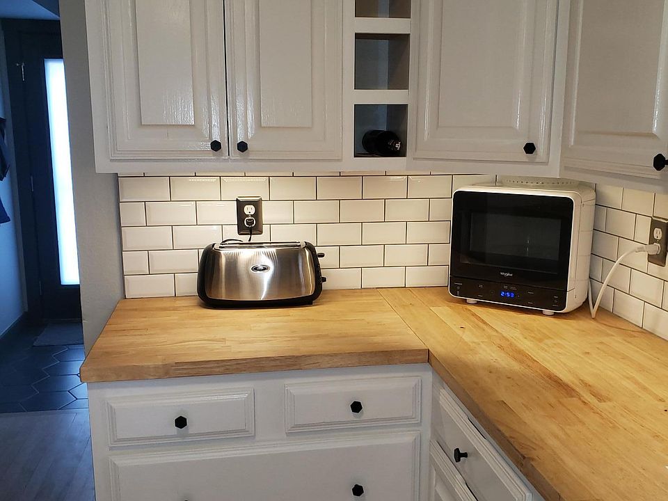 Microwave, wine rack, tile backsplash.