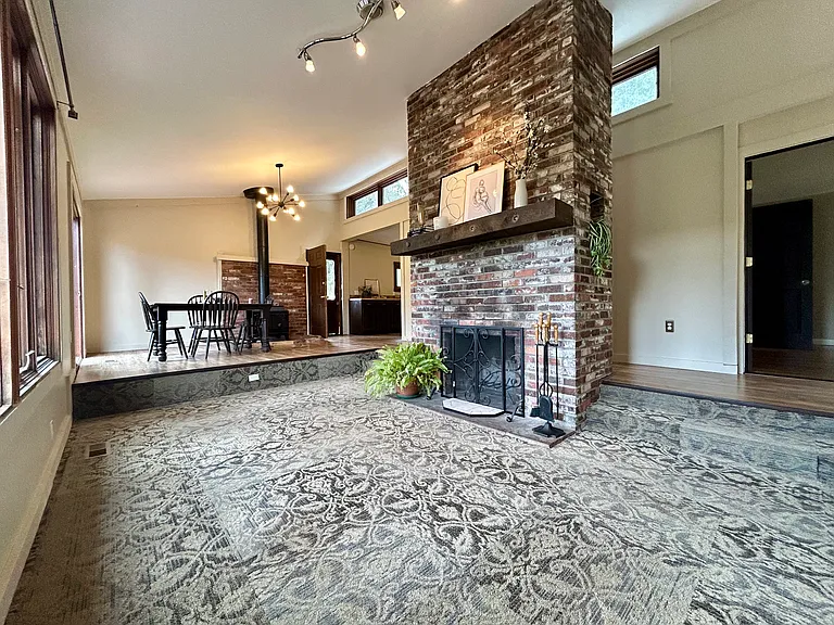 Large floor to ceiling wood burning fireplace in the living room with skylights along the back wall