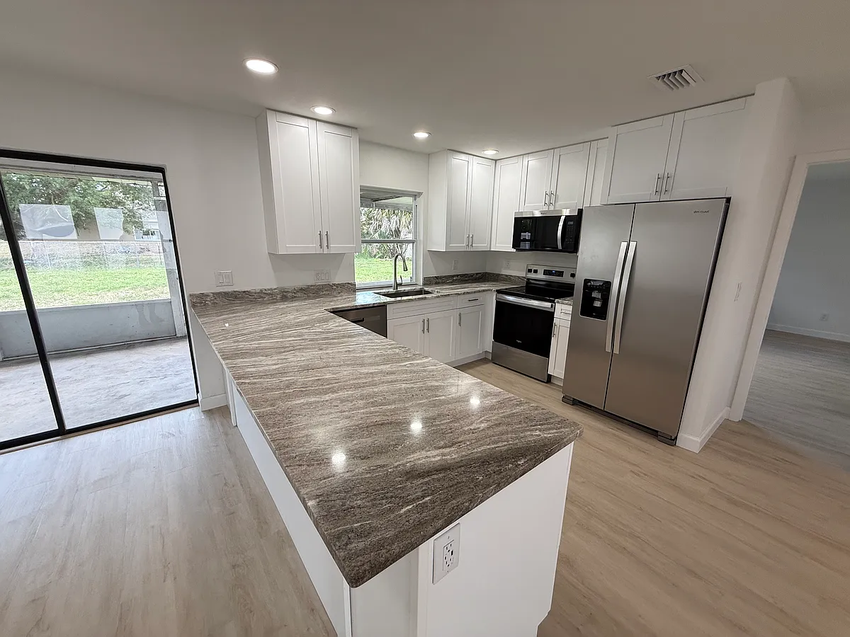 Kitchen overlooking lanai with sliders and a passthrough window. - 3222 SW 6th Pl