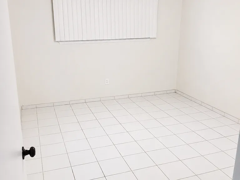 Comfortable second bedroom with neutral walls, tile flooring, ceiling fan, and closet space.