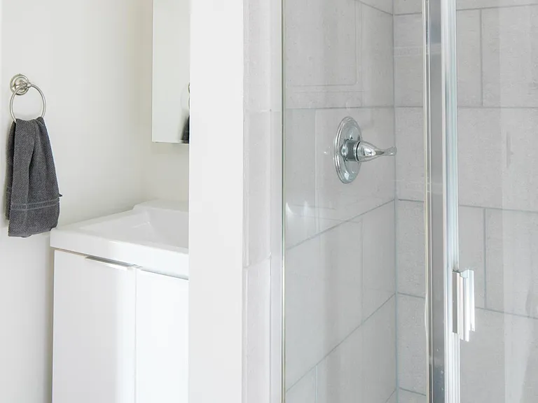 Updated bathroom with pocket door includes stacked washer/dryer and tiled shower