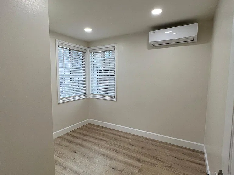 Bedroom with mini split and mirrored closet.