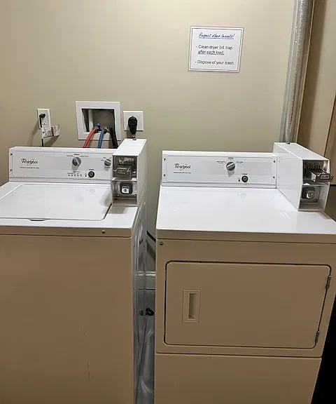 Bright and clean laundry room features 2 washers and 2 dryers.