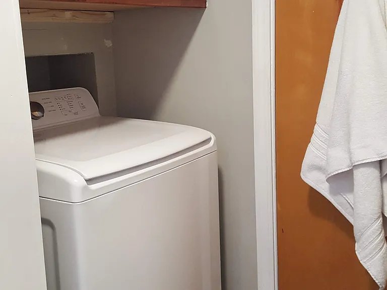 Washing machine in bathroom with storage cabinet above