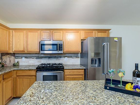A pretty kitchen remodel has granite counters, stainless appliances and tile backsplash. The tile floors are also recently installed.