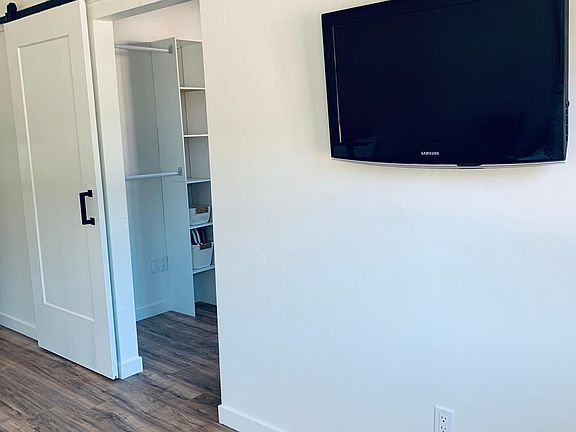 Living space and bedroom are separated by sliding barn door for privacy. Wall mount flat screen TV with streaming capabilities.
