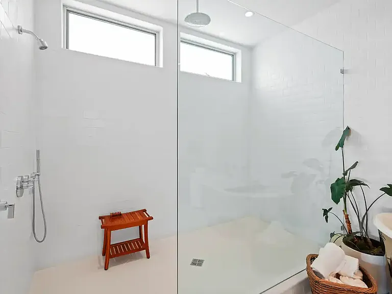 Walk-in shower with high-end fixtures and a bench.