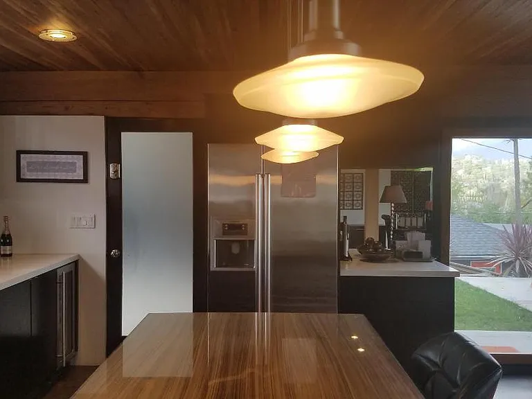 Stylish mid-century kitchen with zebra wood accents, custom cabinetry, stainless steel appliances, and a built-in wine refrigerator.