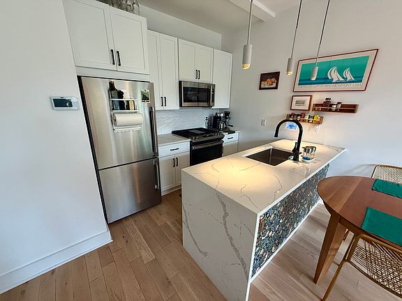 Waterfall quartz kitchen peninsula with designer pendant lighting