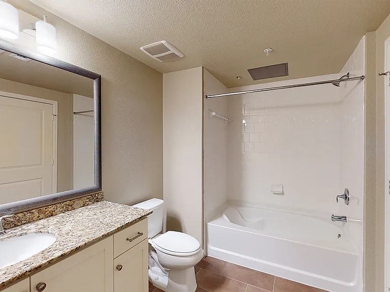 Apartment bathroom with large soaking tub and wood-style flooring.