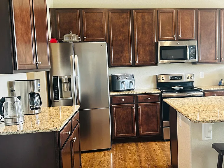 The kitchen has wood floors and stainless steel appliances.