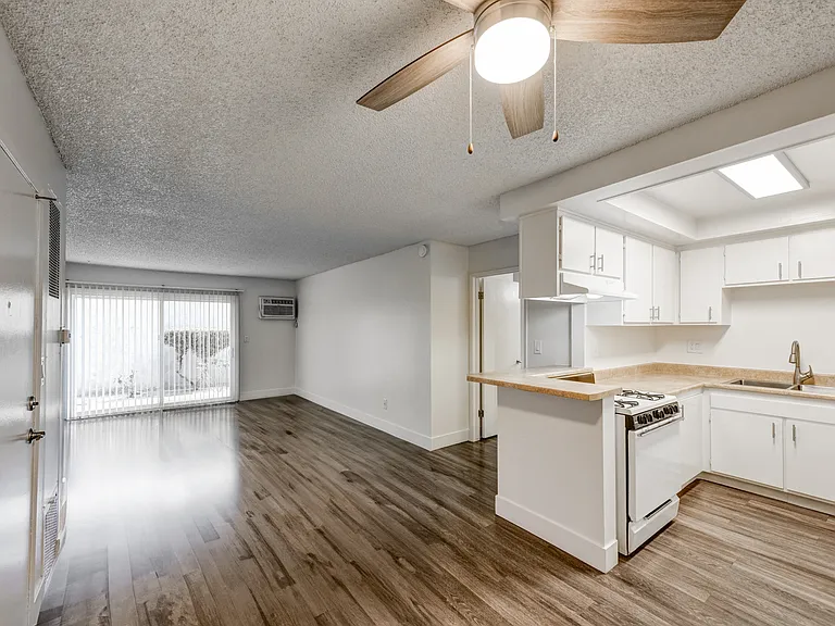 an open kitchen and living room with white cabinets and wood floors