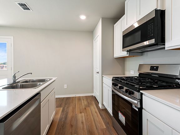 Kitchen featuring Quartz countertop and appliances with stainless steel finishes, white cabinetry, dark wood-style flooring, recessed lighting, and light stone counters