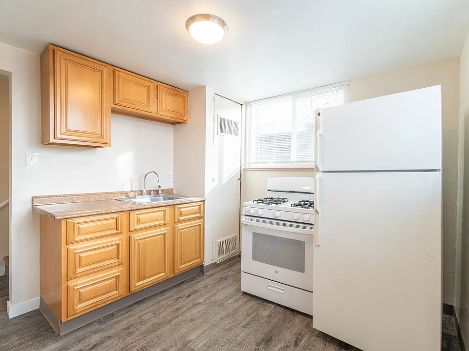 Bright kitchen with modern wood cabinets, sleek countertops, and a spacious layout featuring a large fridge and essential appliances.