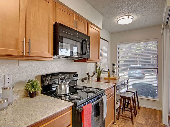 A kitchen with light cabinets and black appliances