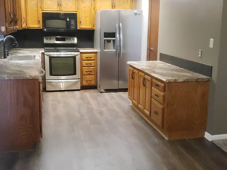 Kitchen with microwave, refrigerator, stove, and dishwasher. Lots of cabinet space. New flooring.