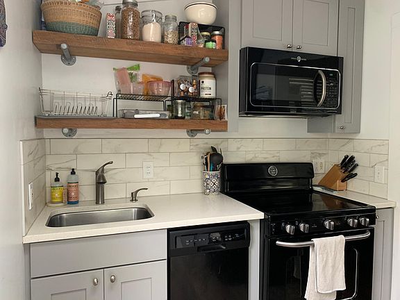 Cozy kitchen with newer appliances, dishwasher, garbage disposal, tile backsplash and neutral cabinets and countertops, reclaimed lumber shelves.