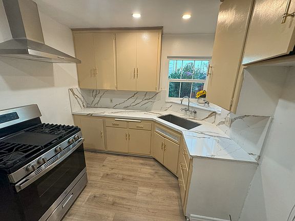 Remodeled kitchen with new paint, flooring, kitchen hardware, quartz countertop, led lights, range hood and range included.