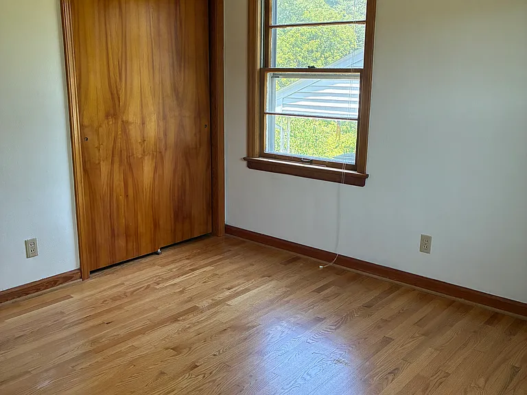 Second bedroom with hardwood floors, closet storage, and natural light.