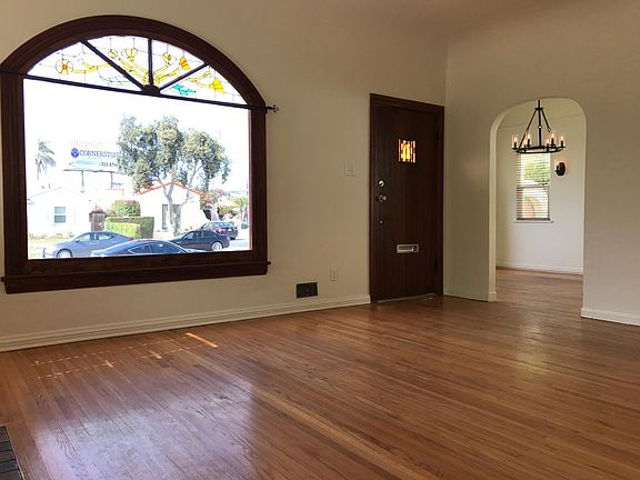 Living room with original hardwood floors (refinished since photo was taken), stained glass arched windows, arched doorway to dining room for fluidity in entertaining!