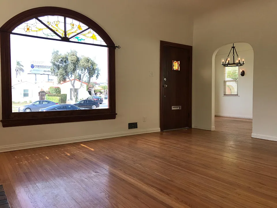 Living room with original hardwood floors (refinished since photo was taken), stained glass arched windows, arched doorway to dining room for fluidity in entertaining!