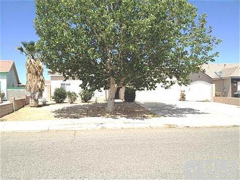 Front of house with large shade tree, bushes and rod iron dr