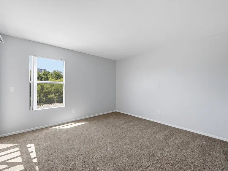 A room with a window showing a view of trees and a building outside.
