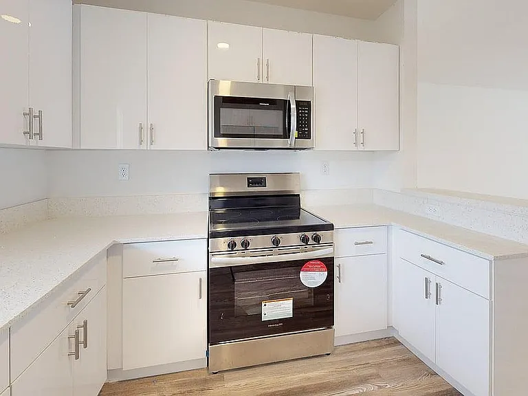 Bright modern kitchen with sleek stainless steel appliances, elegant white cabinetry, and polished countertops.